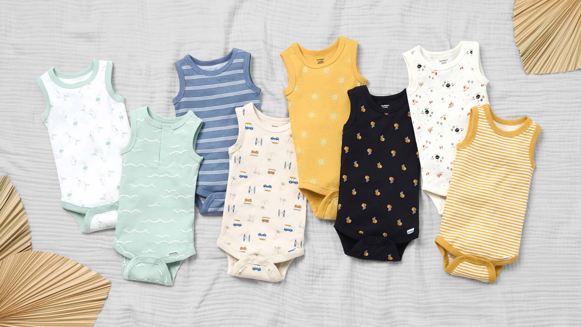 Assortment of baby bodysuits in various colors and patterns displayed on a textured background.