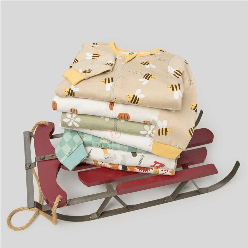 Stack of baby clothes on a red sled with a light gray background