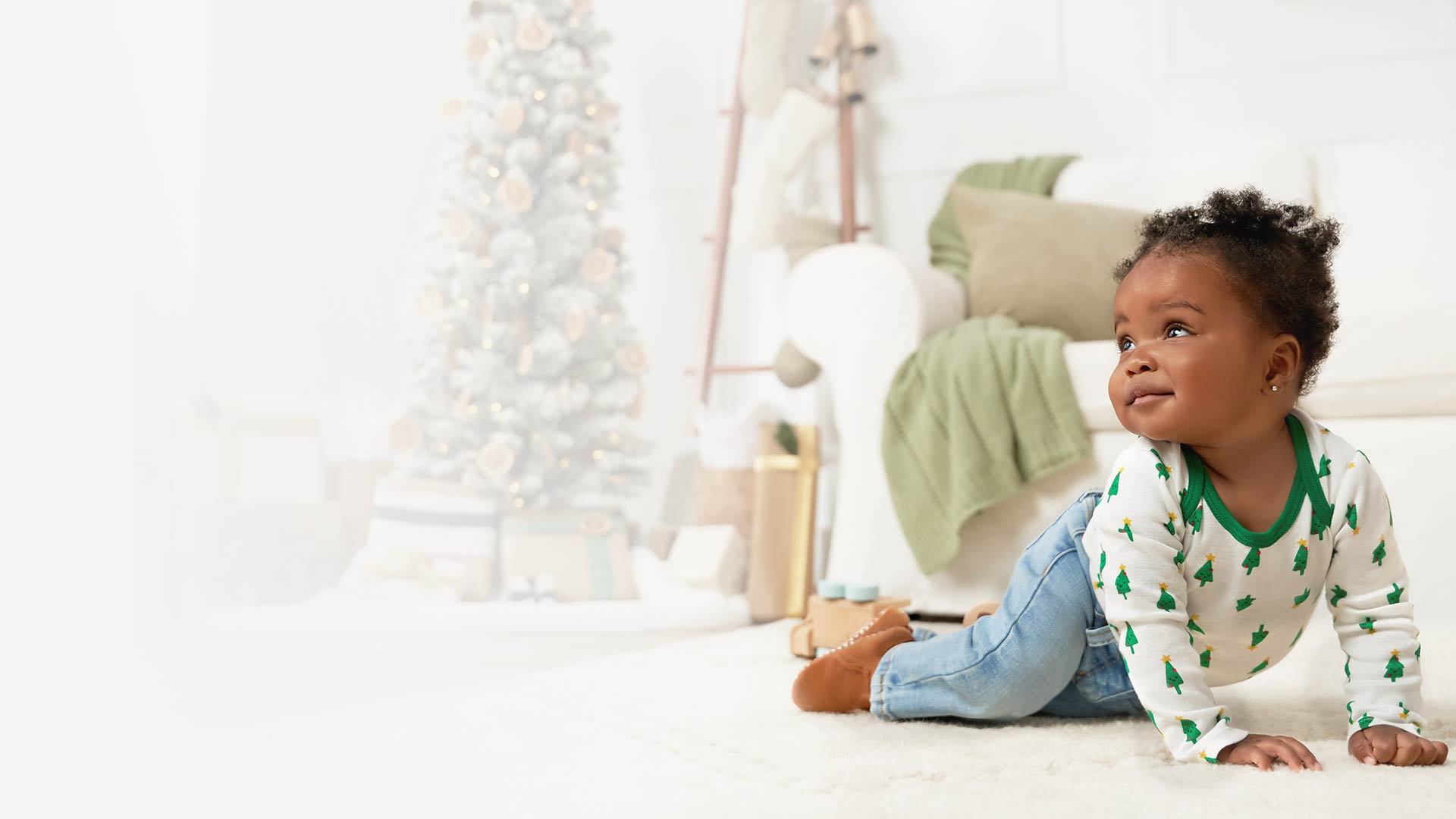A precious infant eagerly exploring the floor, enchanted by the magical presence of a Christmas tree adorned with ornaments.