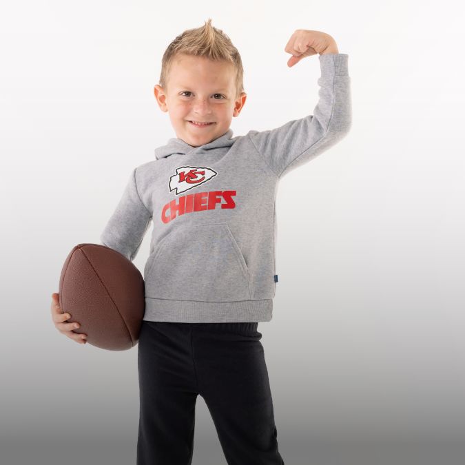 Toddler boy wearing a Kansas City Chiefs hoodie holding an American football.
