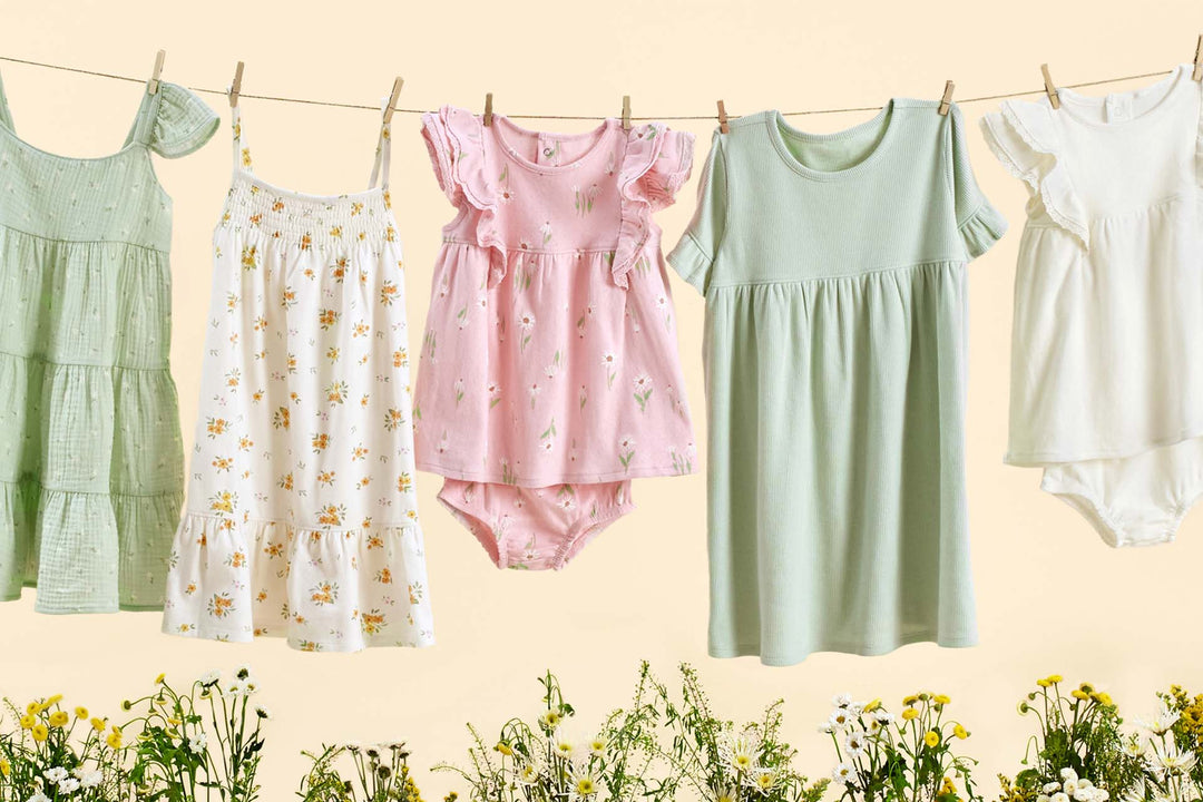 Toddler girl clothes hanging on a clothesline with flowers in the background.