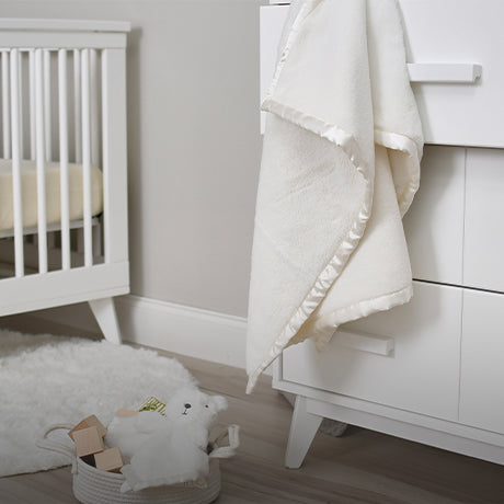 An adorable white crib adorned with a soft white blanket and a lovable white bear companion.