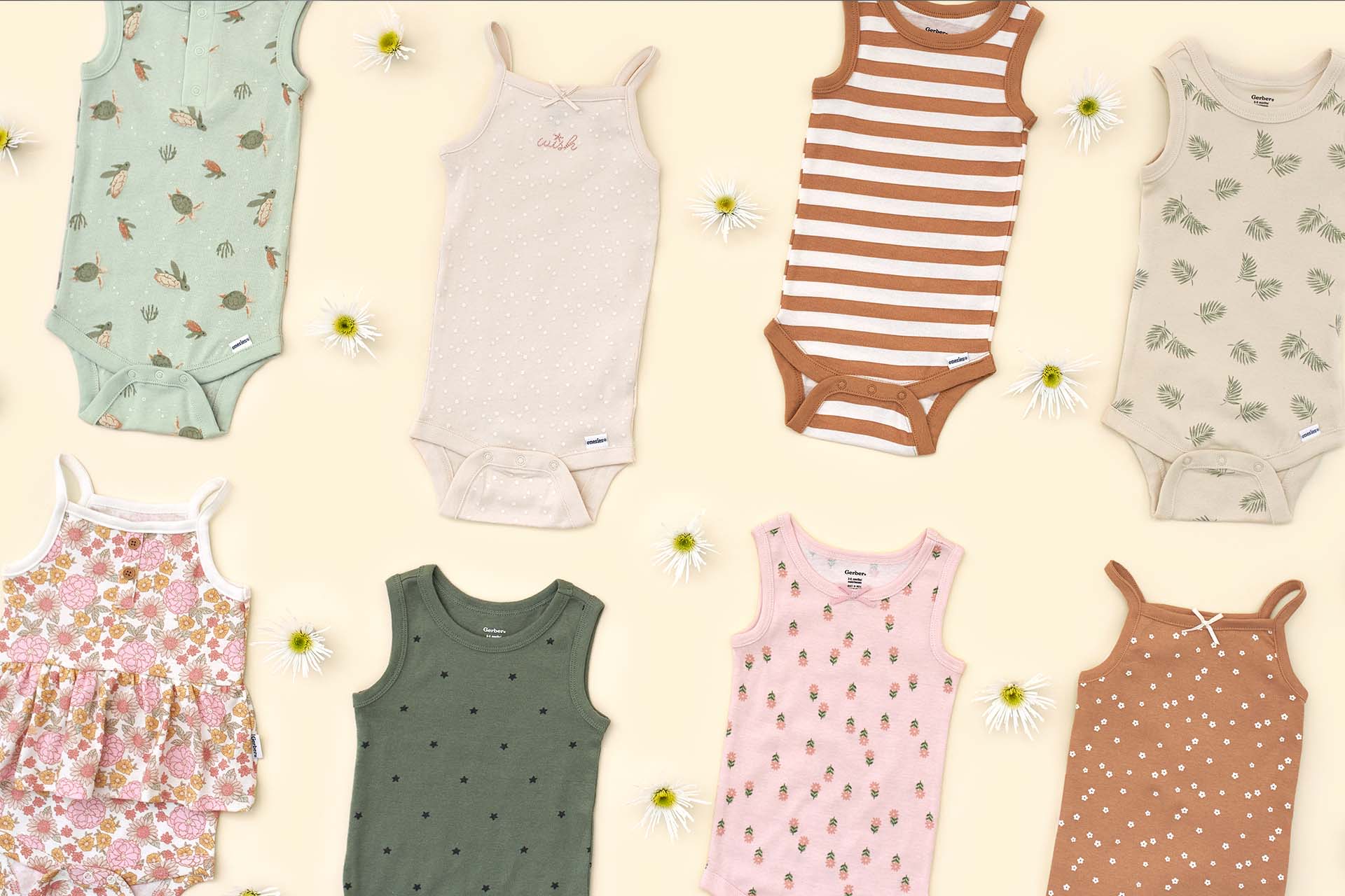 Flat lay of various baby onesies bodysuits with a daisy flowers on a pastel background.