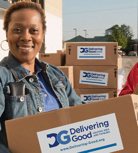African American woman holding a cardboard box that has a sticker that says Delivering Good.