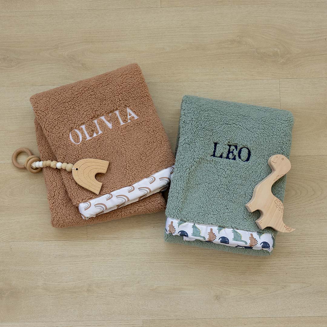 Two baby blankets with name embroidery on a wooden surface