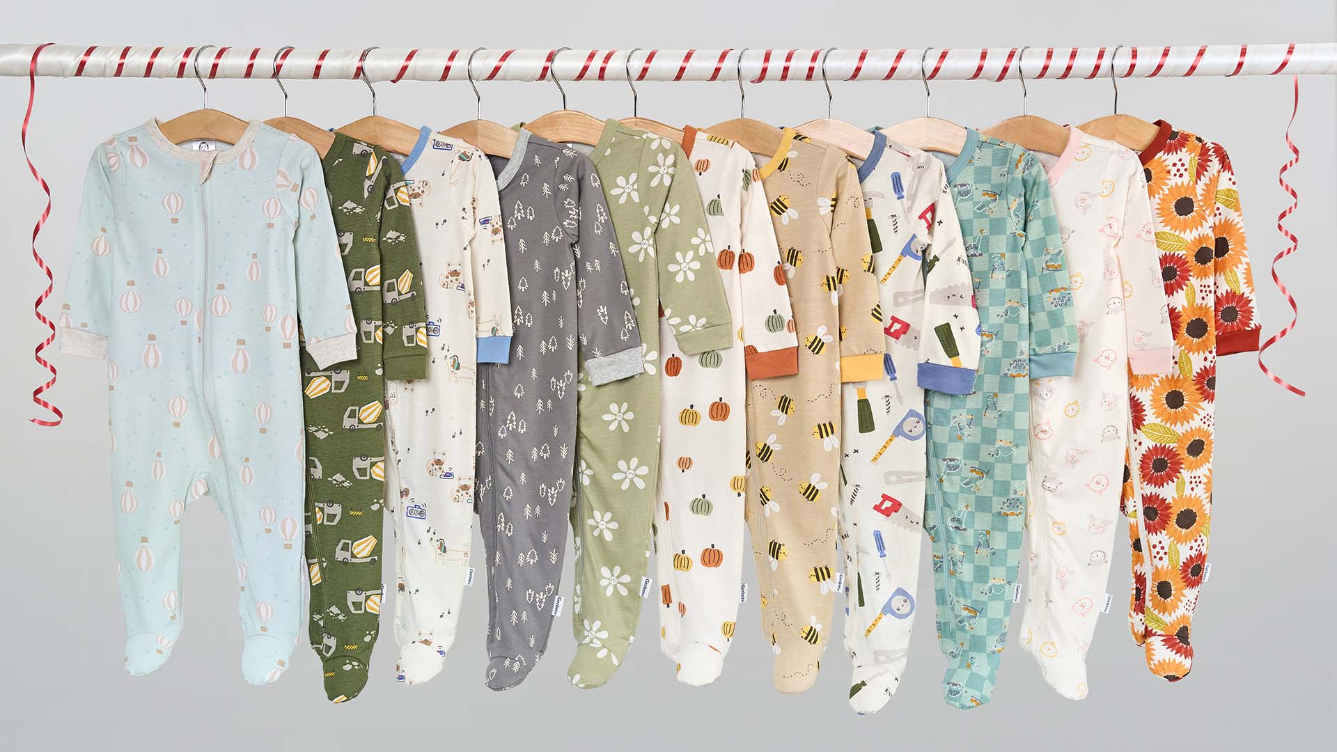 Row of baby onesies with various patterns on a rack against a light background