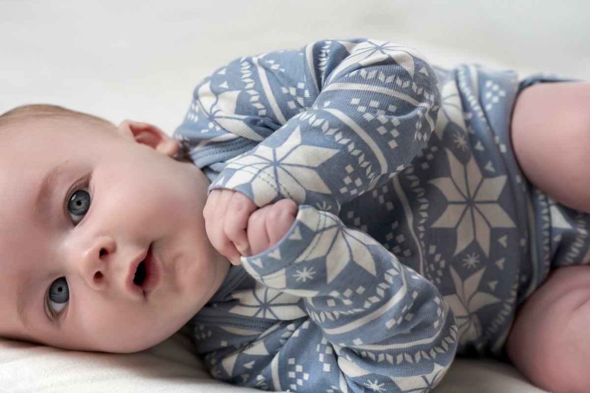 Baby wearing a blue and white patterned onesie on a light background