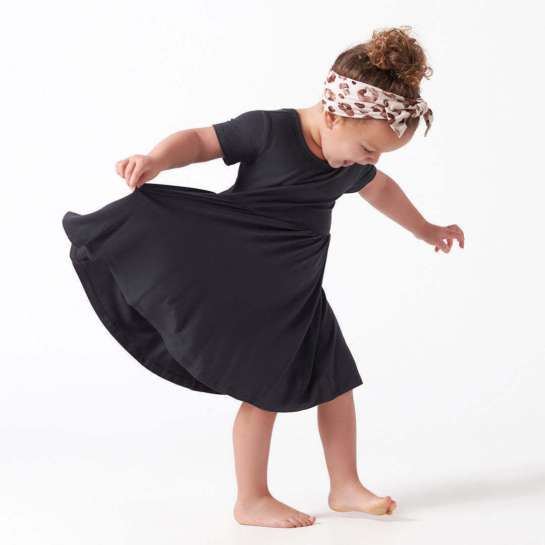 Child wearing a black dress and headband on a white background