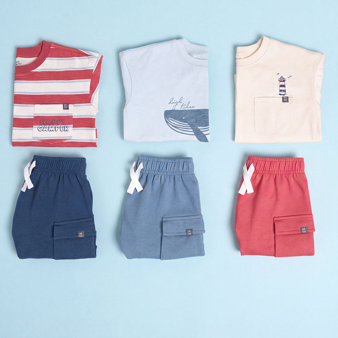 Collection of children's clothing including t-shirts and shorts on a light blue background