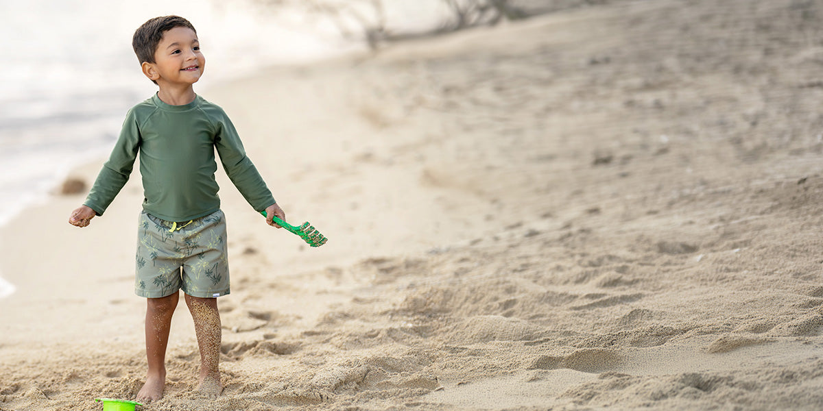 Child playing on a sandy beach with a shovel