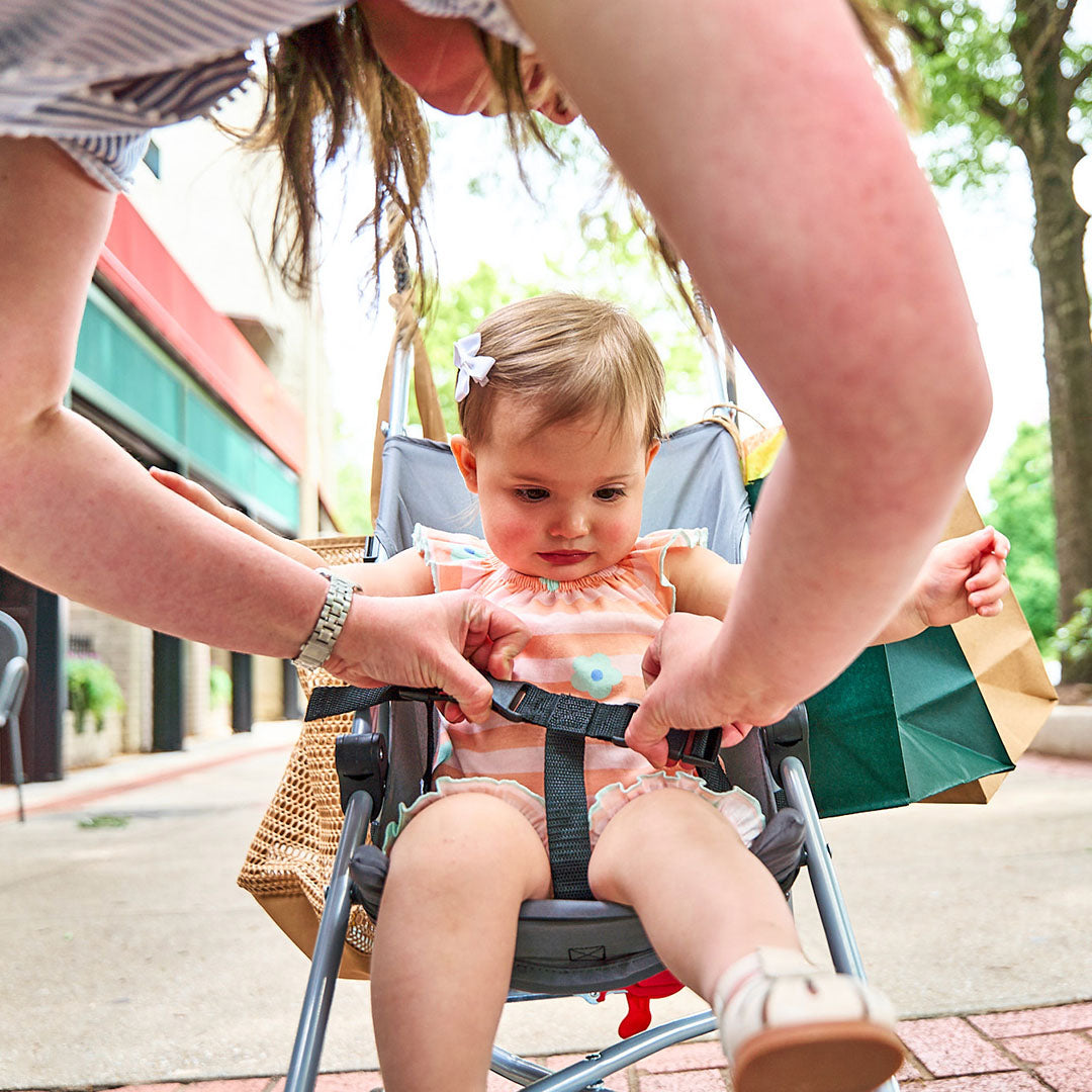 Child in a stroller being helped by an adult outdoors