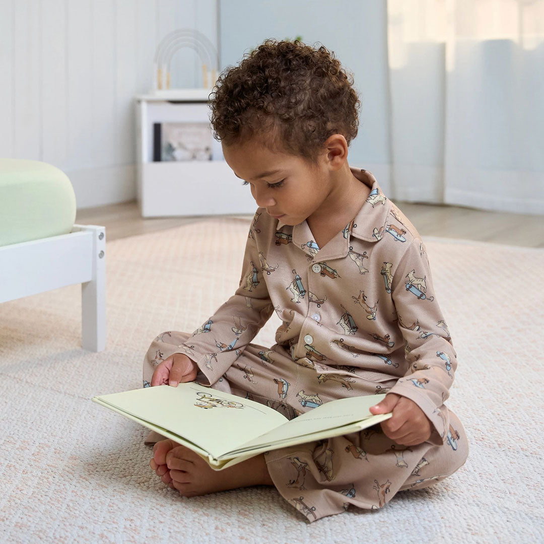 Child in pajamas reading a book on a light-colored carpet