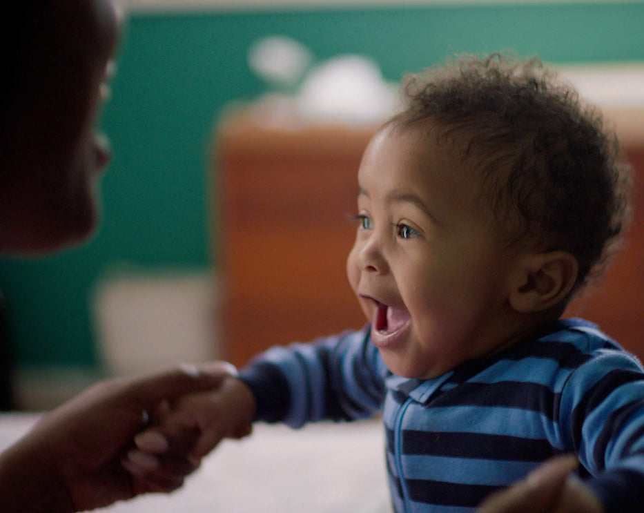Child in a blue striped pajamas interacting with an adult in a home setting