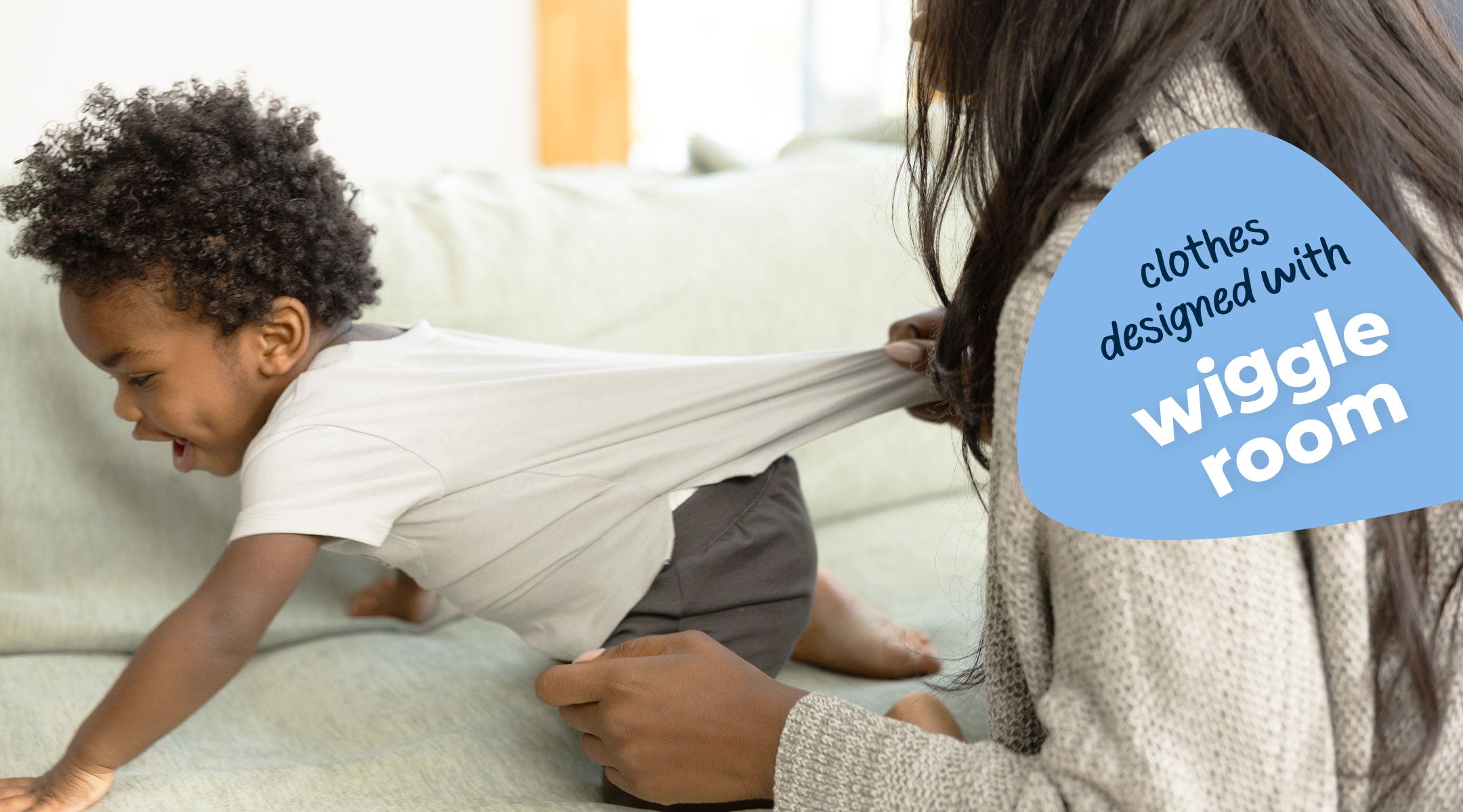 Child playing on a couch with an adult, text 'clothes designed with wiggle room' in a blue speech bubble.
