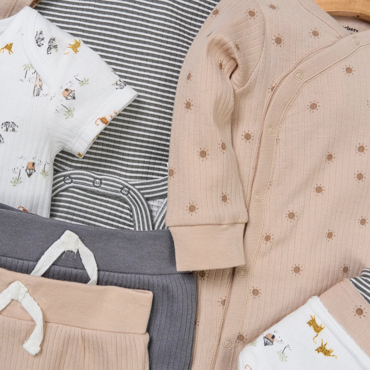 Collection of baby clothes including a beige cardigan, striped shirt, and patterned pants.