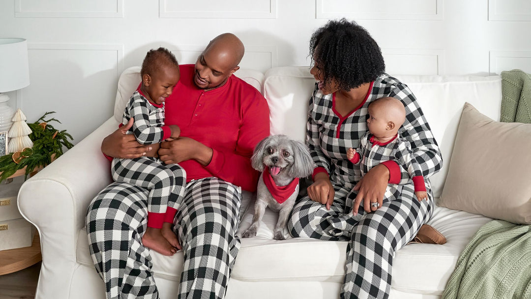 A family of four is seen sitting on a couch, all dressed in matching pajamas.