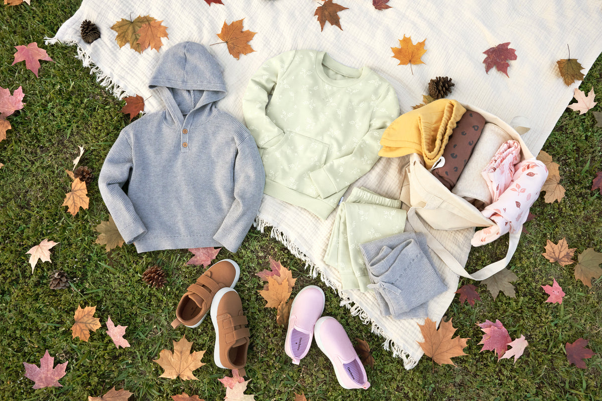 Boy and girl clothing on an autumn blanket laying lawn with leaves.