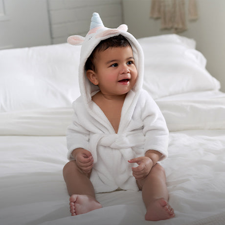 Adorable baby girl wrapped in a soft unicorn towel, looking cozy and cute!