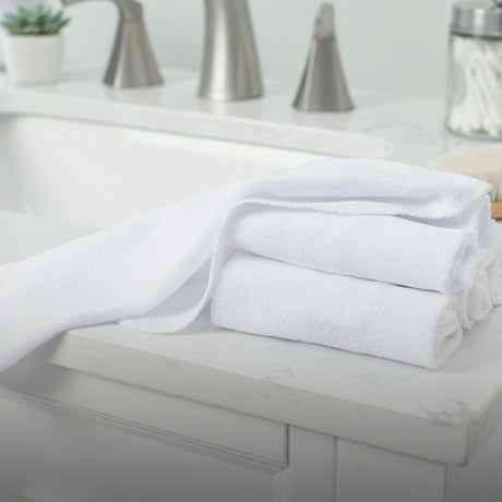 Pristine white towels sitting on a counter in a bathroom.