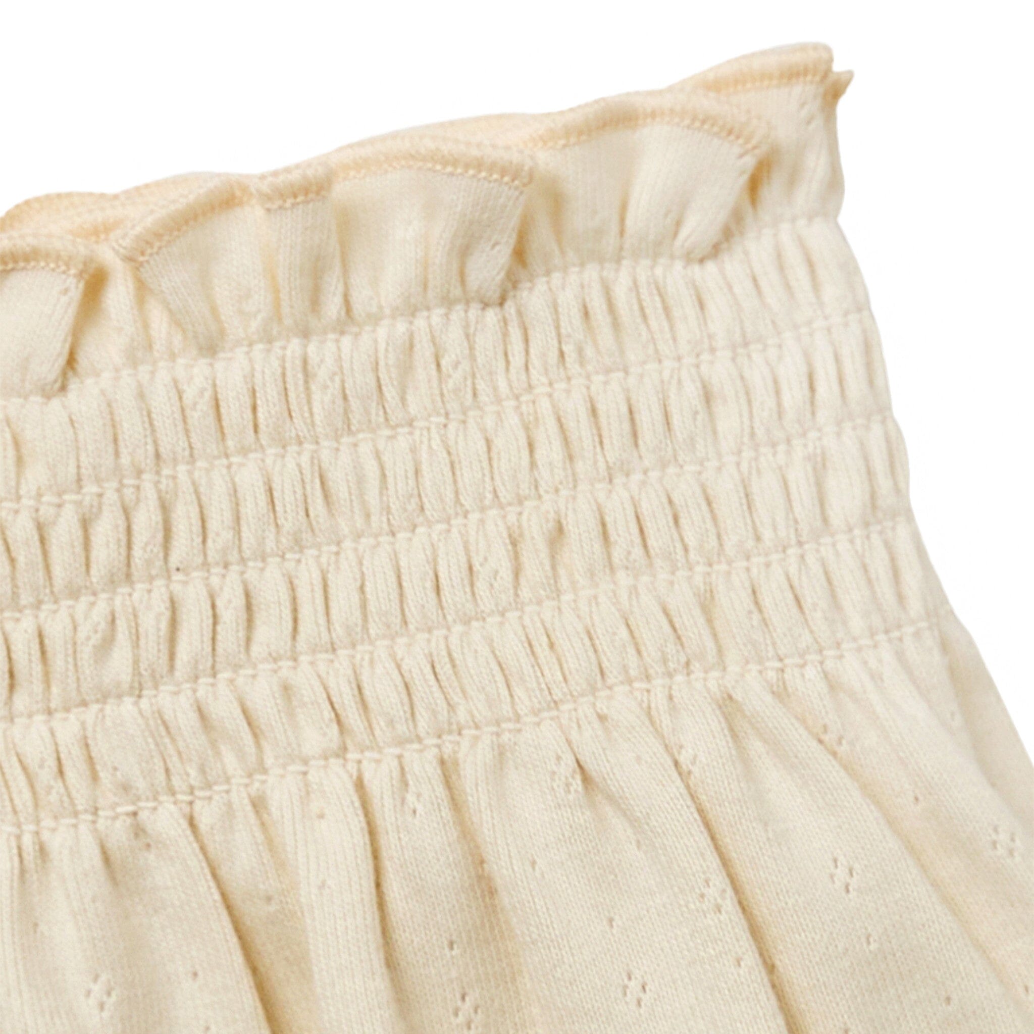 Close-up of a cream-colored fabric with ruffled texture on a white background
