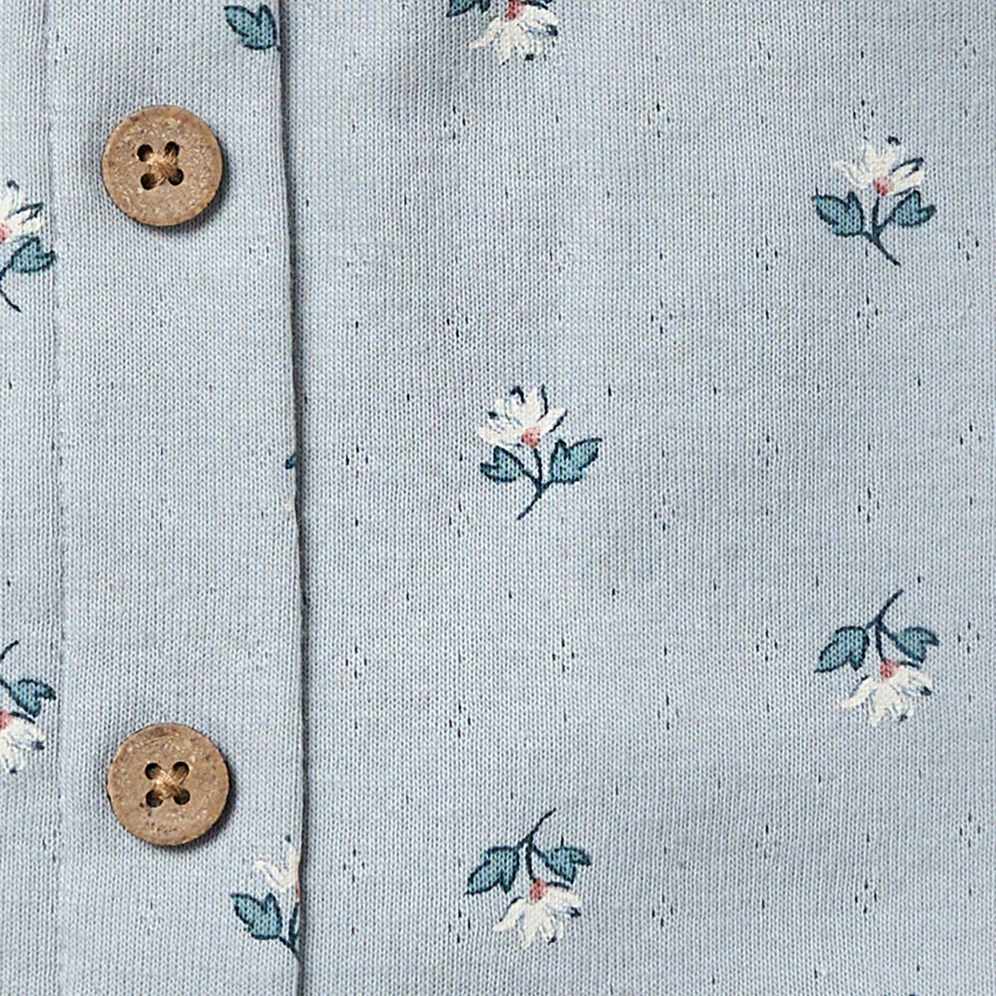 Floral patterned fabric with two wooden buttons on a light blue background