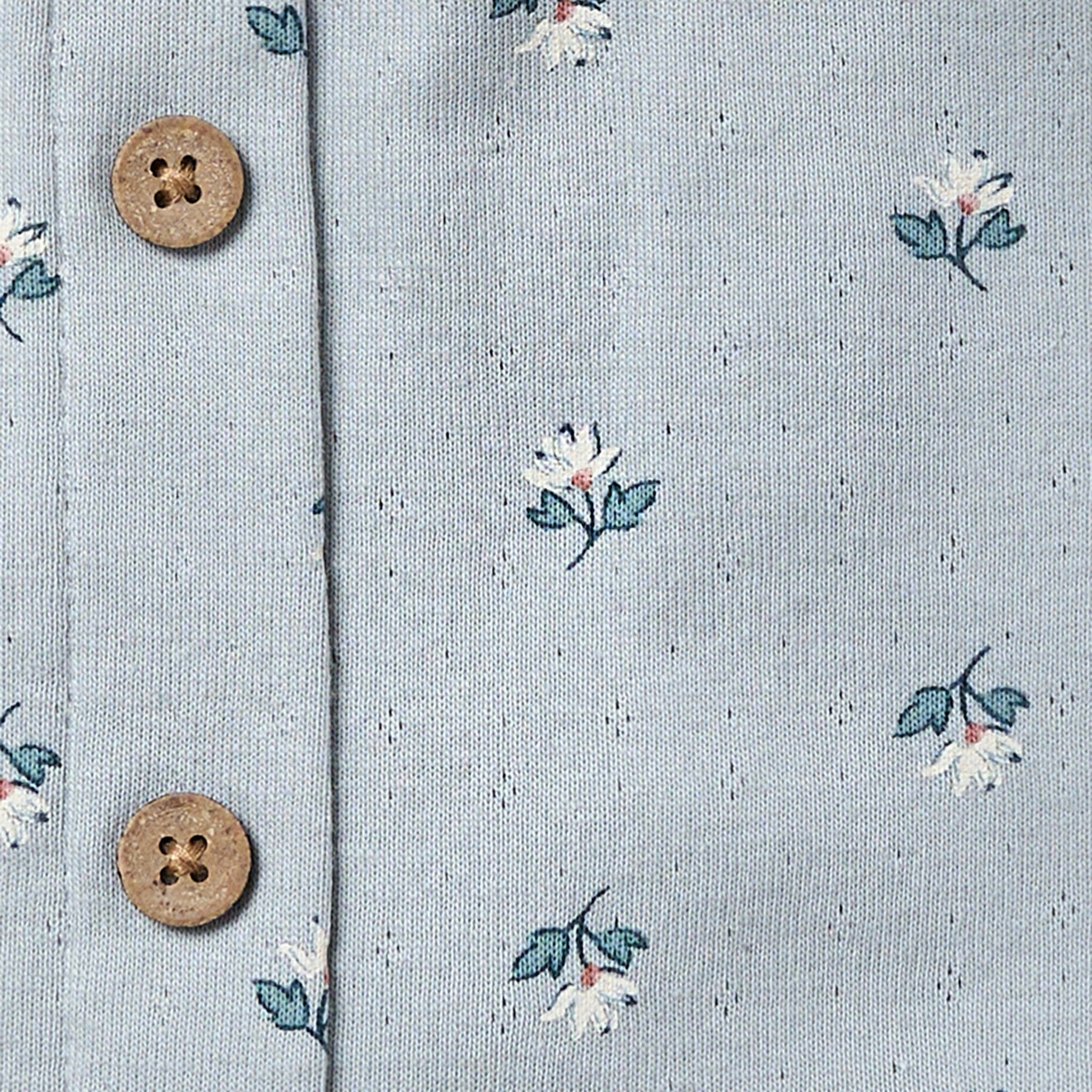 Floral patterned fabric with two wooden buttons on a light blue background