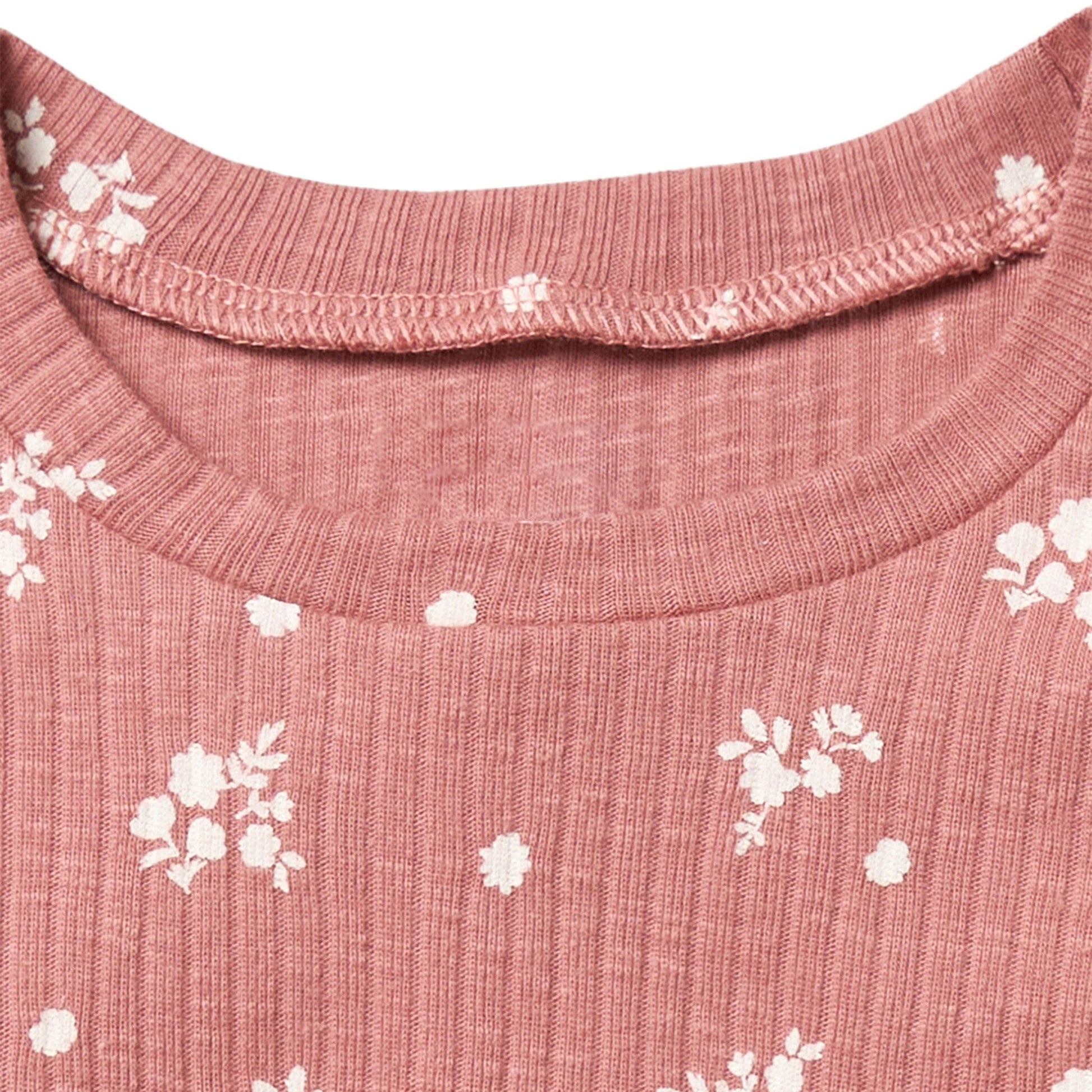 Close-up of a pink garment with white floral patterns on a white background