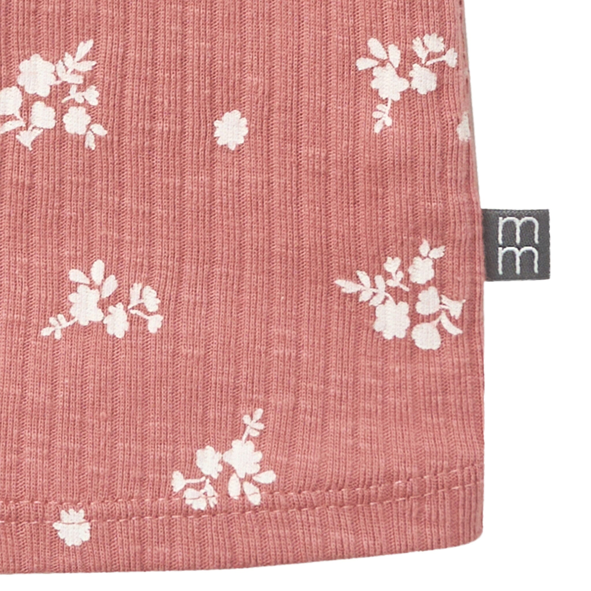 Pink fabric with white floral pattern and a visible brand logo.