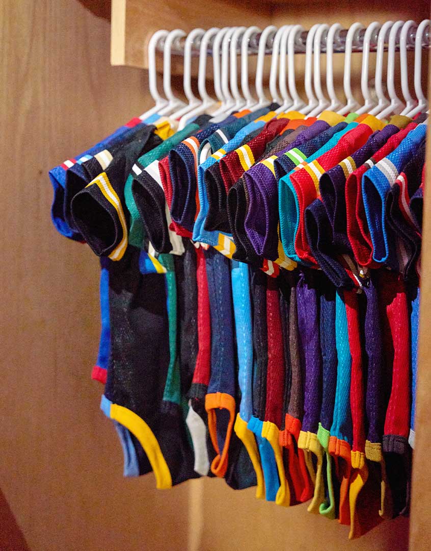 Colorful baby bodysuits hanging on a rack against a wooden background