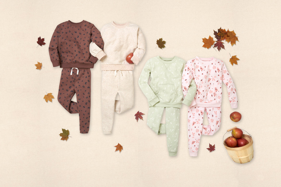 Fall toddler girl outfits in a row on a flat tan background.