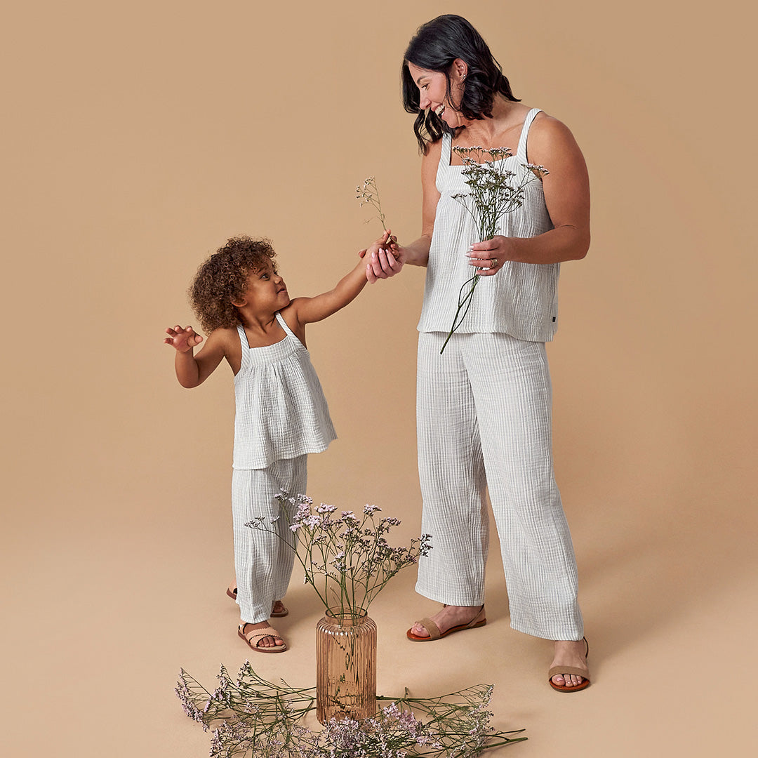 Mom and daughter smiling in matching striped outfits while holding flowers. Click here to find family fashion for special moments.